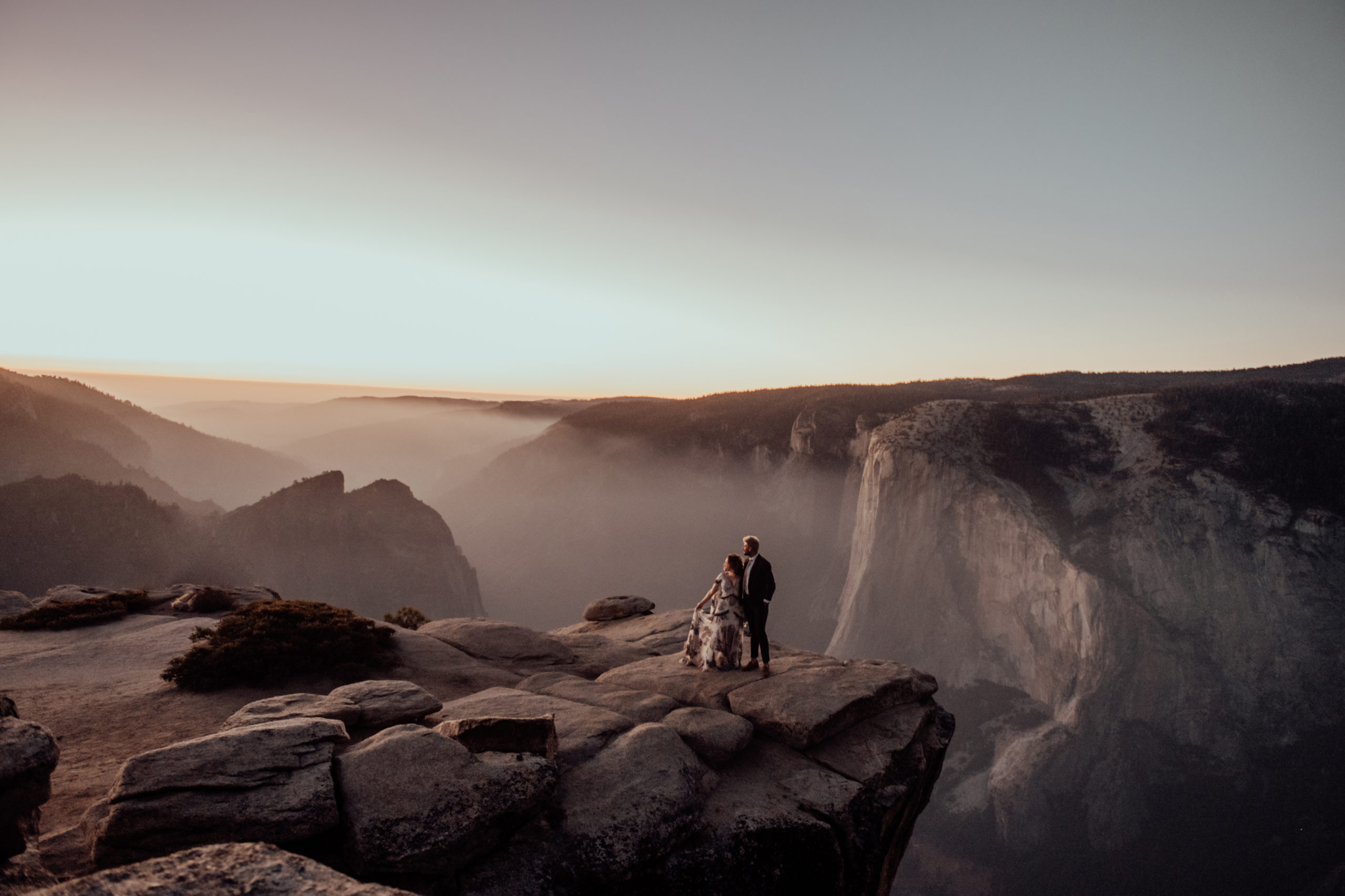 bride and grrom kissing on the cliff at Yosemite National park in California