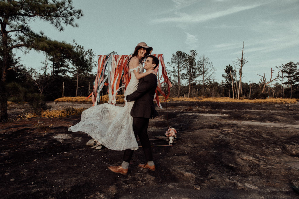 groom picking up the bride and twirling her at their elopement at Arabia Mountain in Georgia