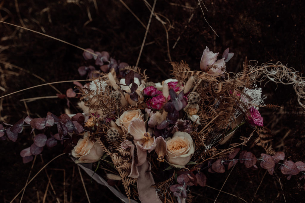 photo os the bridal bouquet with pink flowers laying on the ground 