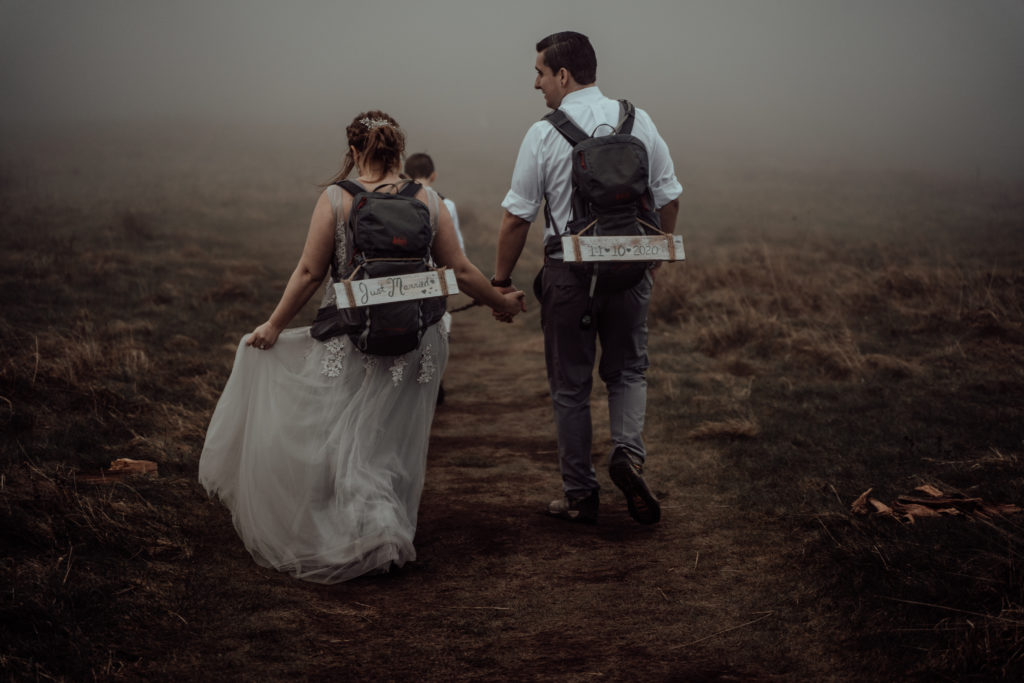 bride and groom holding hands and walking down the mountain after their elopement in max patch on blue ridge parkway north carolina 