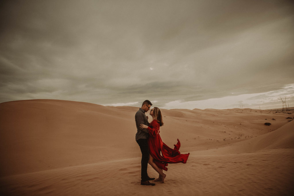 Photo os the couple looking at each other taken at the Glamis sand dunes in California 