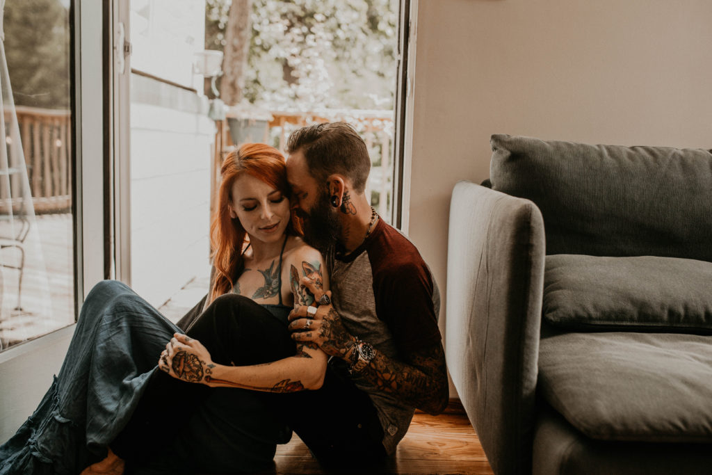 photo of the couple with tattoos sitting on the floor with the girl's back against the guy taken at an airbnb in atlanta 