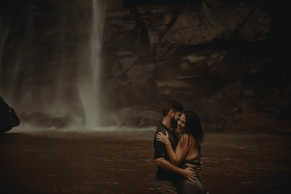 photo of the couple laughing and hugging under the waterfall at Toccoa falls in Georgia 