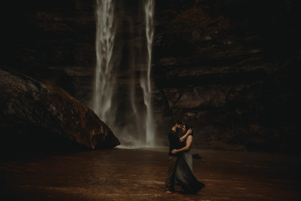 Photo of the couple looking at the each other standing in front of a waterfall taken at Toccoa falls in georgia 