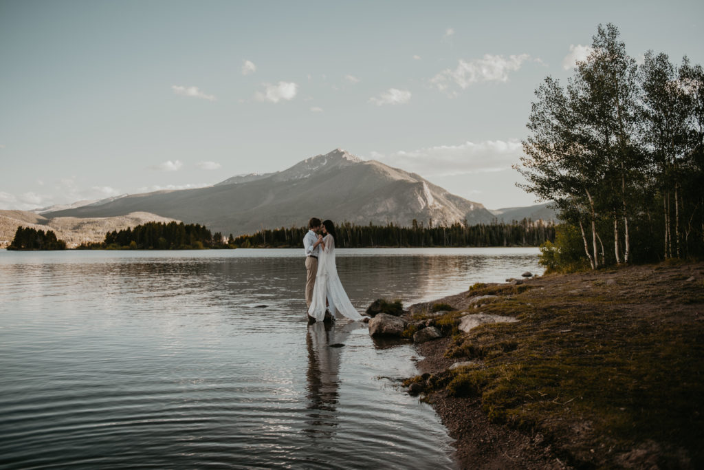 bride and groom standing in the lake and holding hands