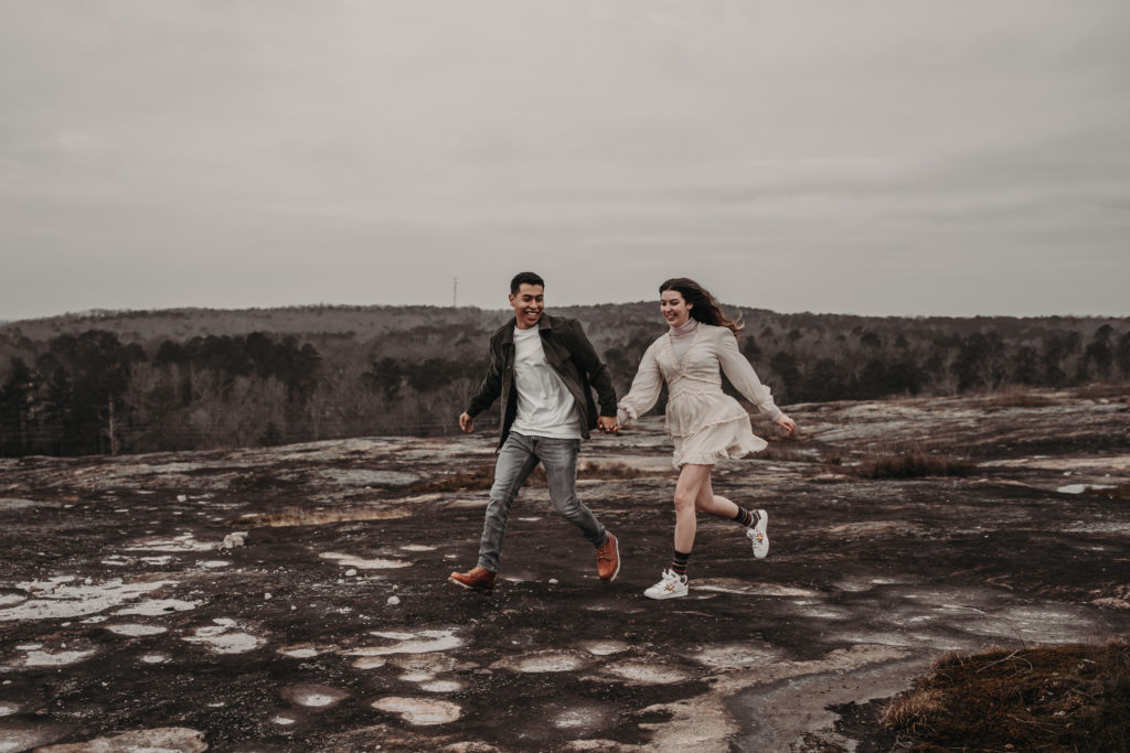 photo of the couple running and laughing at Arabia Mountain georgia 