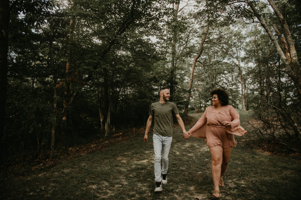 Photo of the couple holding hands and running in a field taken at Cloudland Canyon in North Georgia