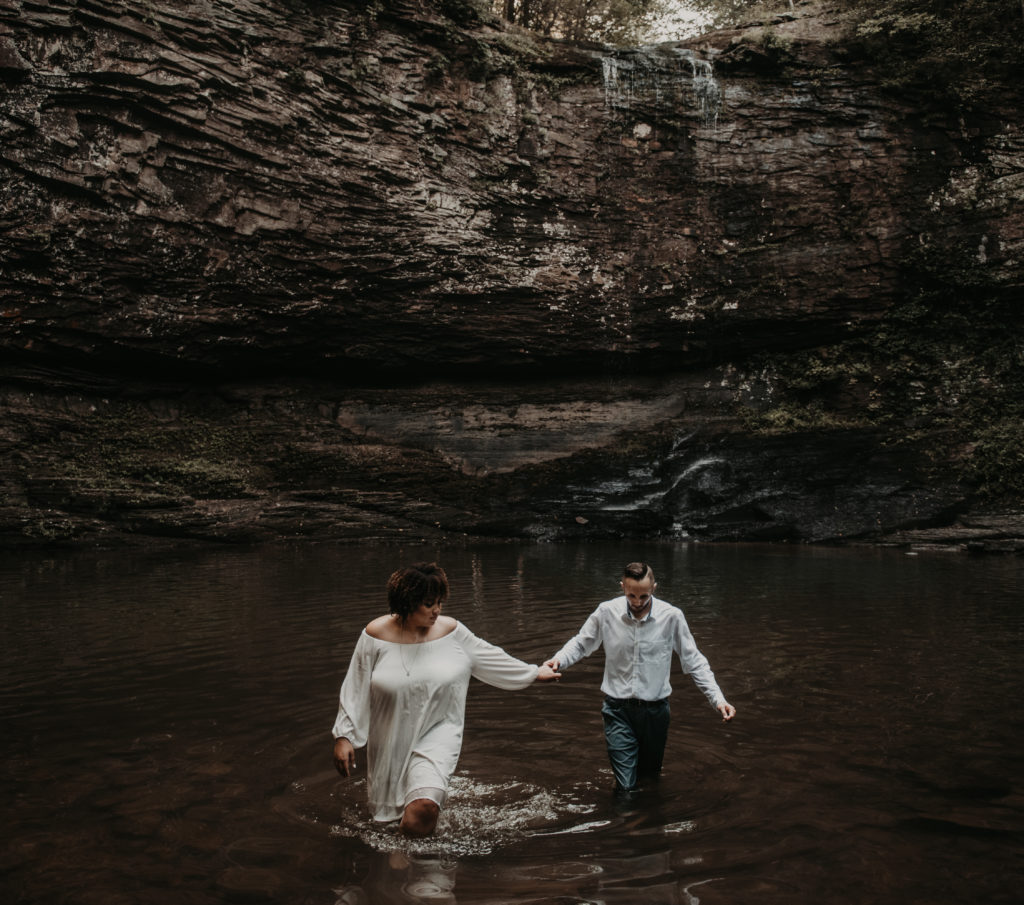 Couple standing in water and holding hands under the waterfall taken at Cloundland canyon in rising fawn georgia 