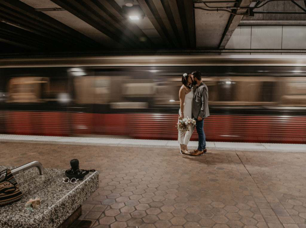 bride and groom kissing on a train station with train moving behind them taken in downtown atlanta