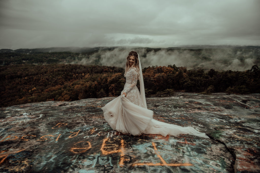 bride twirling her dress on top of a bald mountain during her elopement