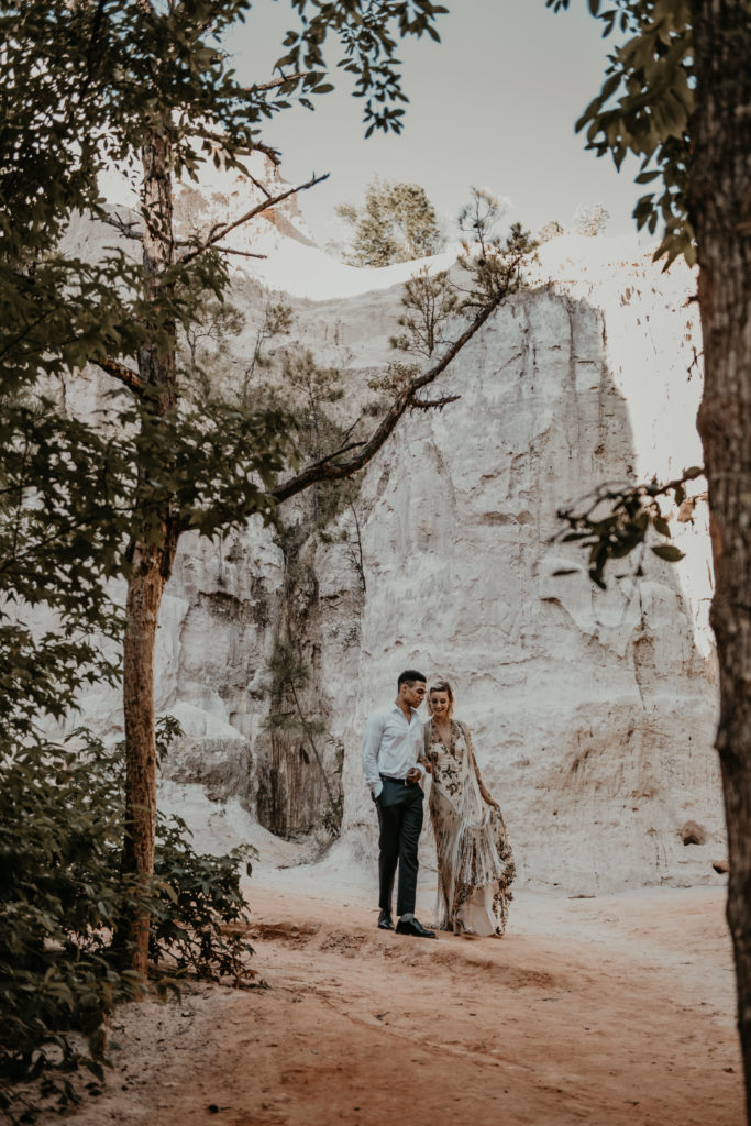Bride and groom holding hands and walking and smiling during their elopement at providence canyon in Georgia