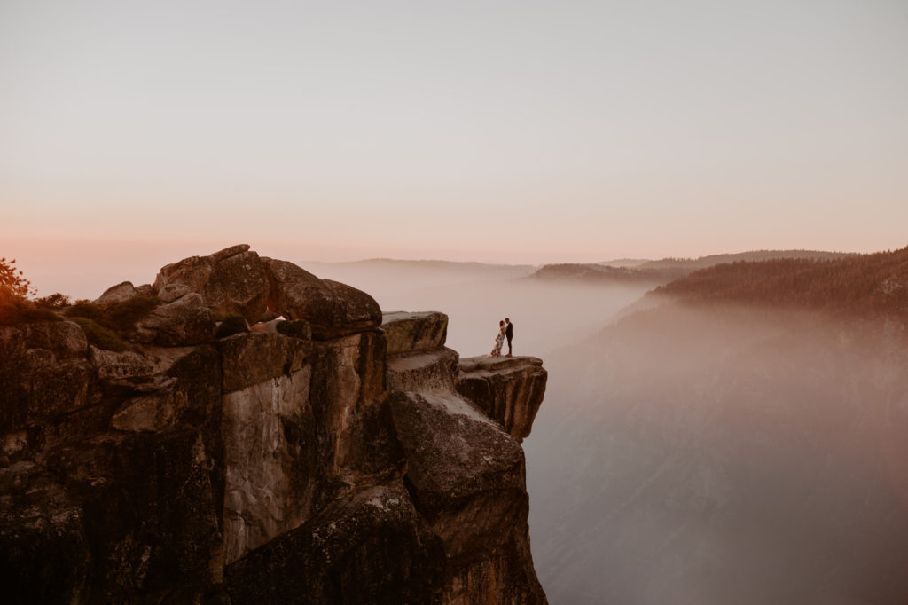 Iconic Taft Point photo of the bride and groom standing on the cliff taken at Yosemite National Park