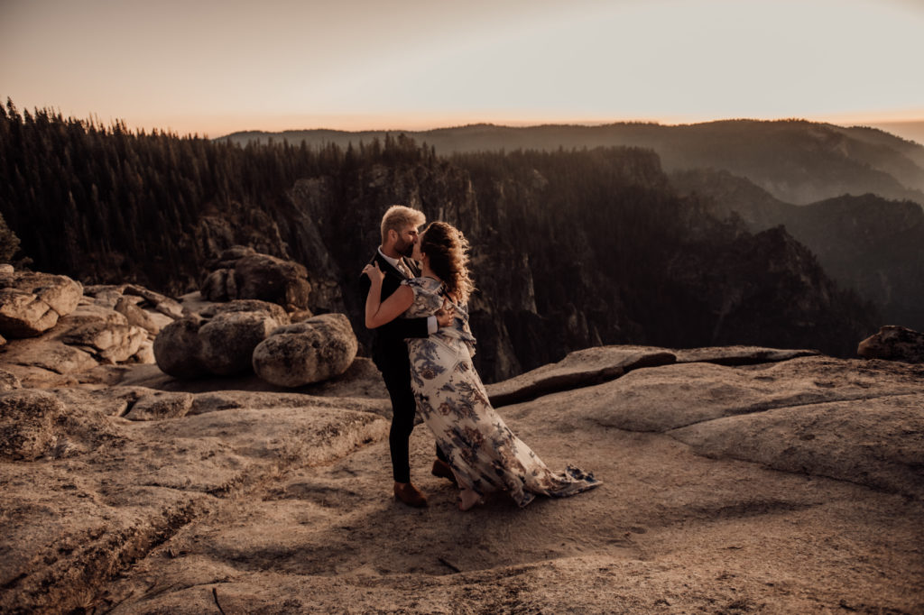 bride and groom hugging and kissing taken on top of the cliff taken at yosemite national park