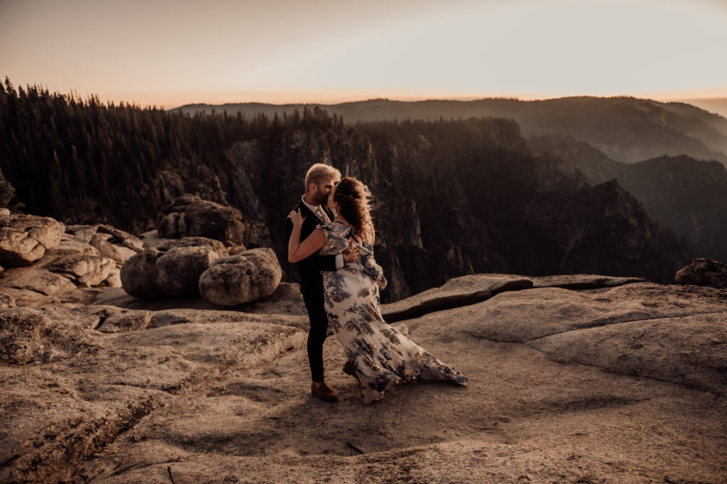 bride and groom hugging and kissing at taft point yosemite during sunset