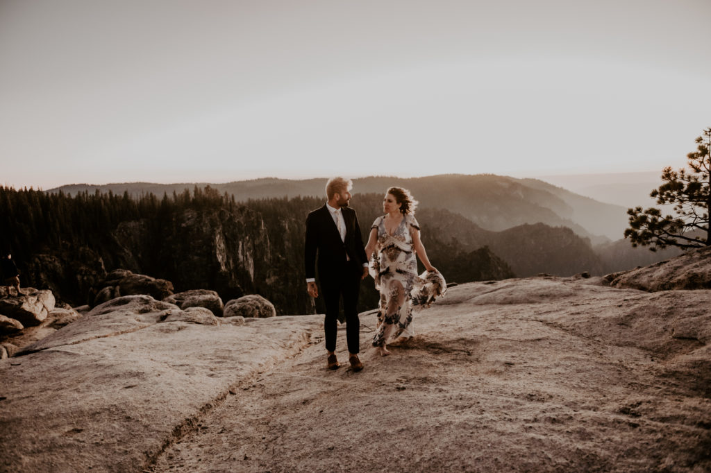 bride and groom holding hands and walking towards the camera taken at yosemite national park