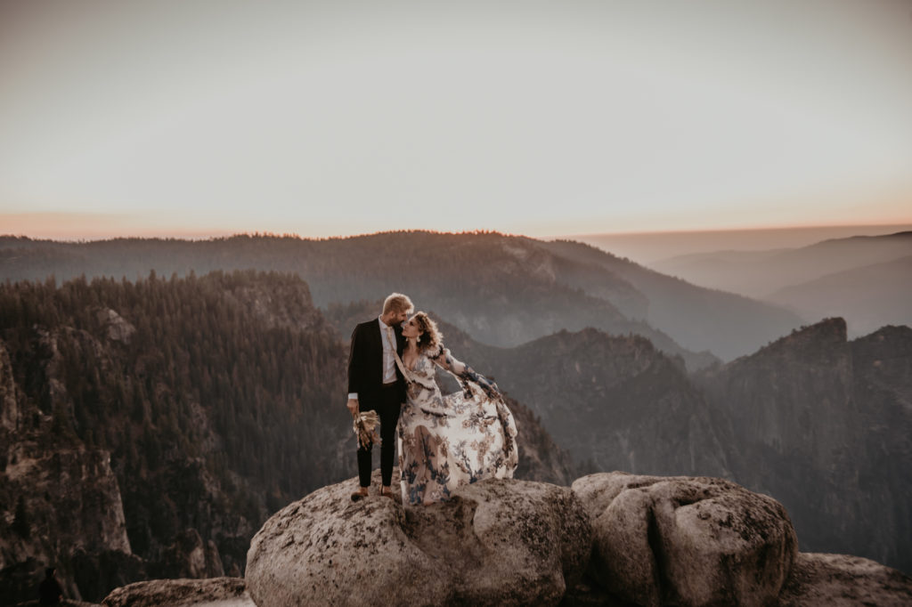 Bride and groom kissing while standing on top of a rock at Yosemite in California