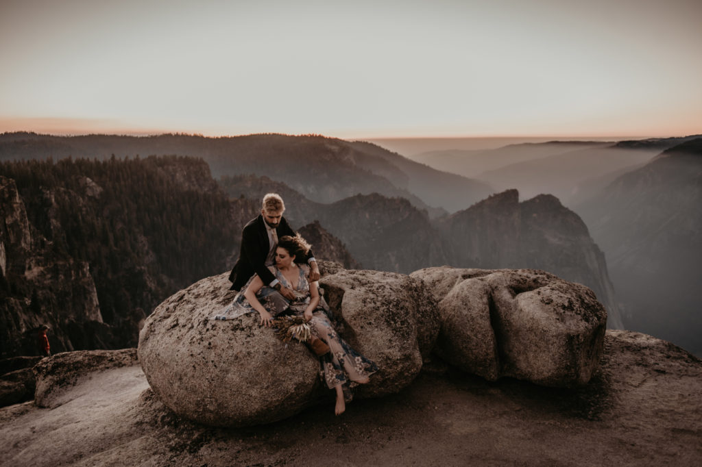 bride and groom sitting on the rock at yosemite national park