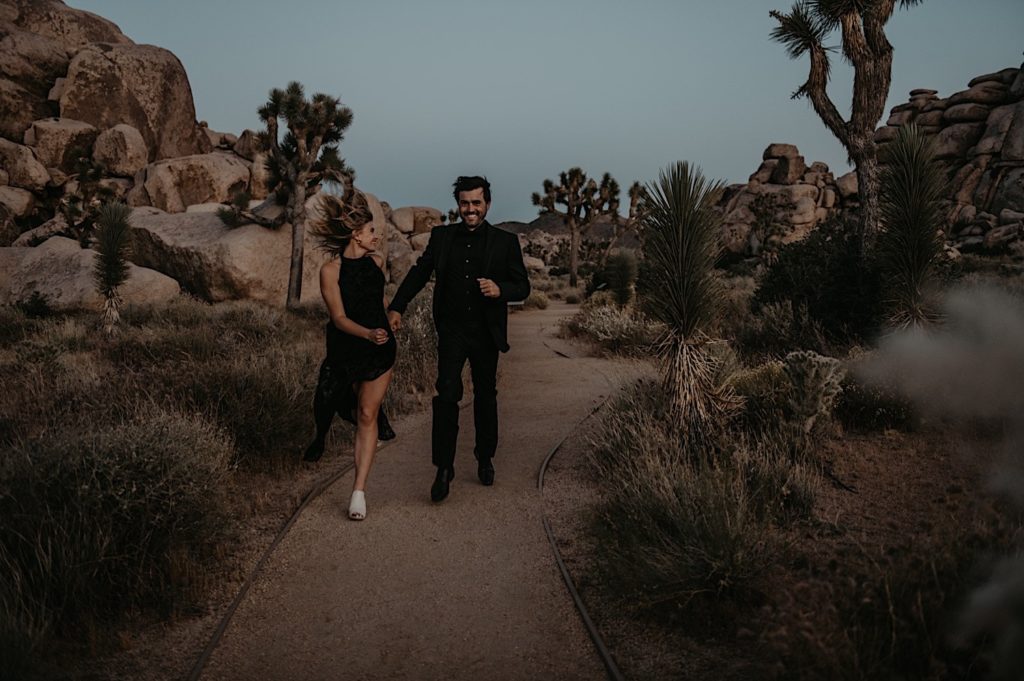 Photo of the bride and groom holding hands and running taken at a Joshua tree elopement