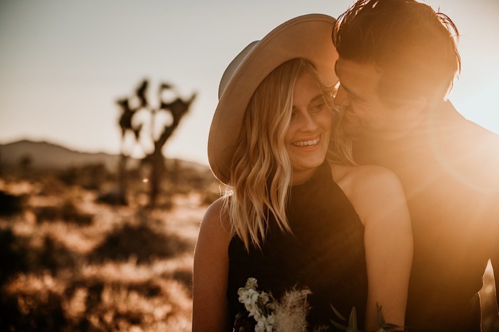 Couple smiling and the sun flares on their faces taken during an elopement at Joshua Tree National park