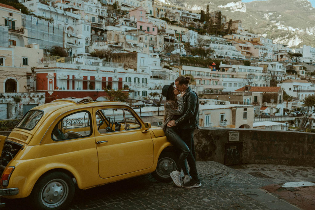 Photo of a couple kissing in front of the family vertical city of Positano ITaly