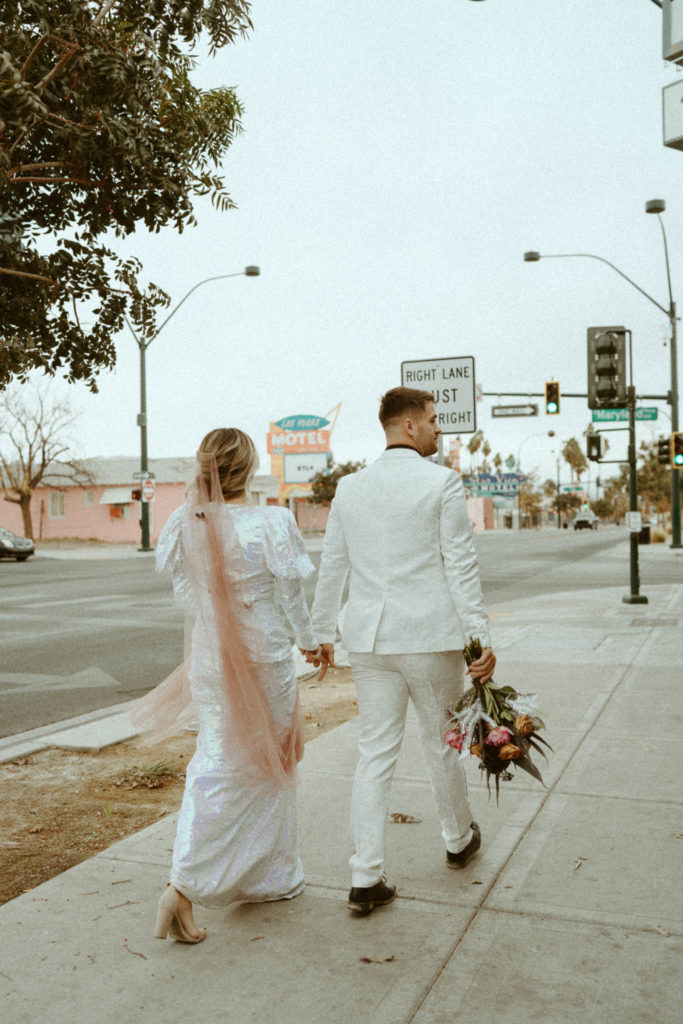 couple holding hands and walking on the streets of vegas after their elopement