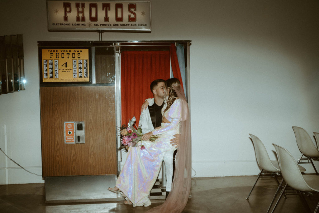 couple kissing inside the vintage photo booth at the sure thing chapel