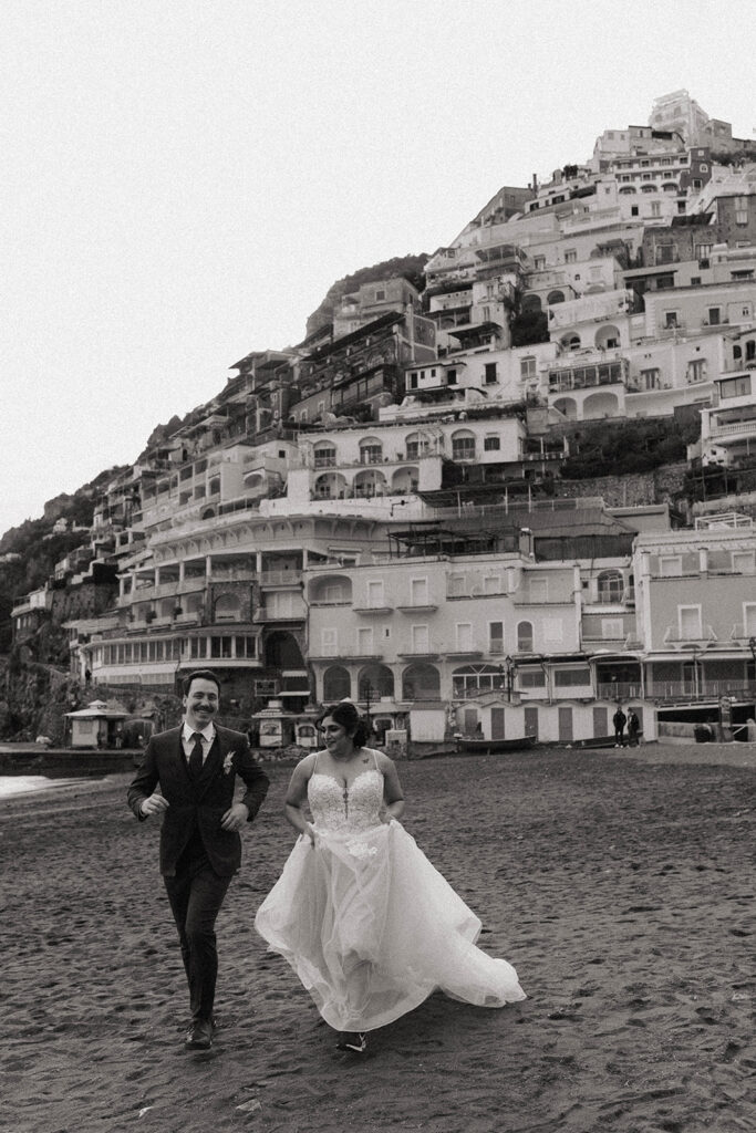 Bride and groom running on the beach from their elopement in Italy