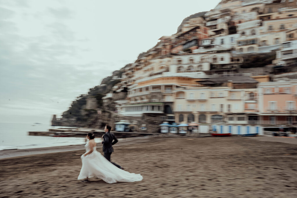 Bride and groom running on the beach from their elopement in Italy