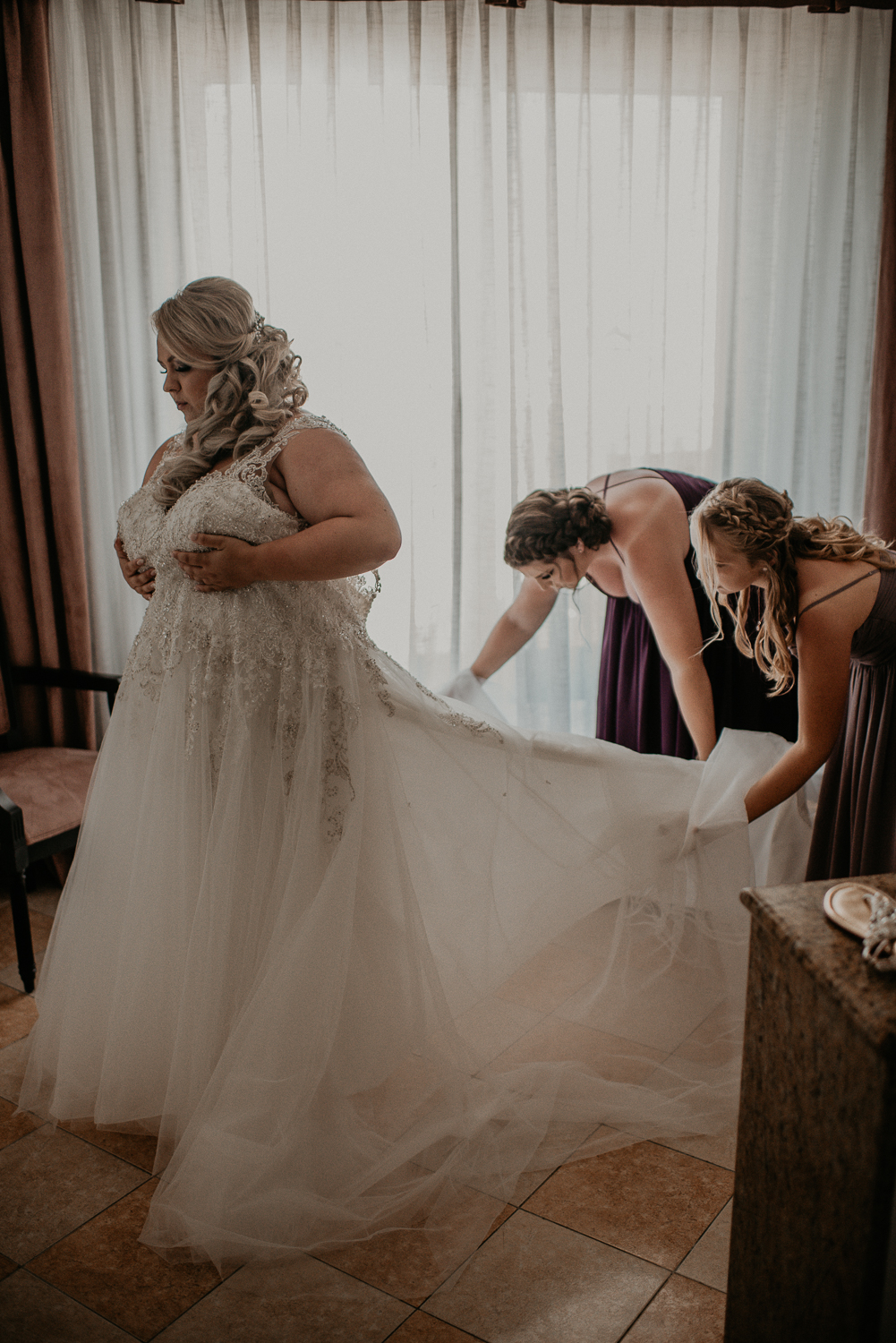 Bridesmaids helping bride with her dress