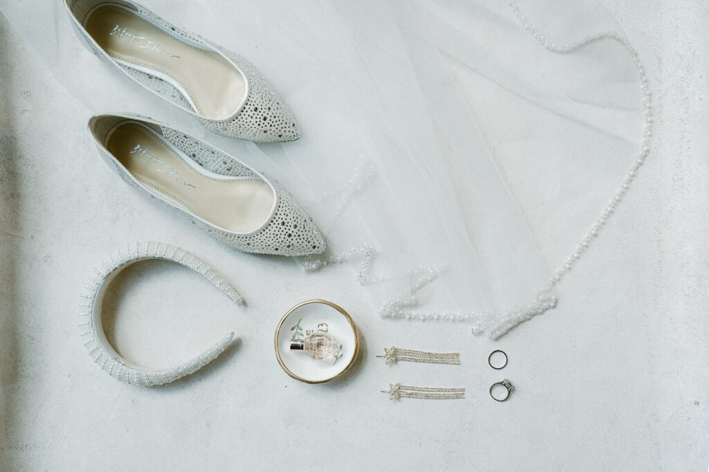 Brides wedding detail with shoes, headband, jewelry, and perfume. 