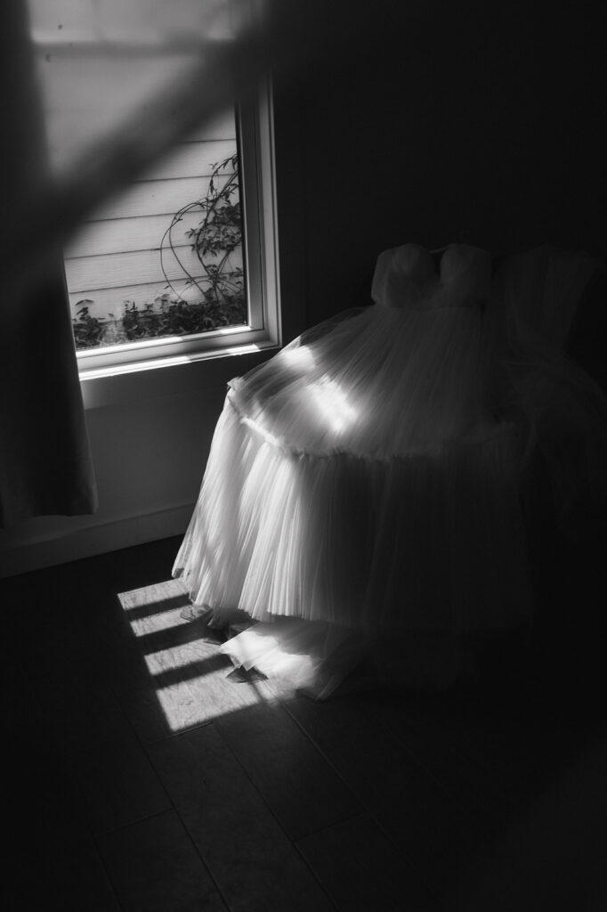 Black and white detail shot of brides wedding dress laying on a chair