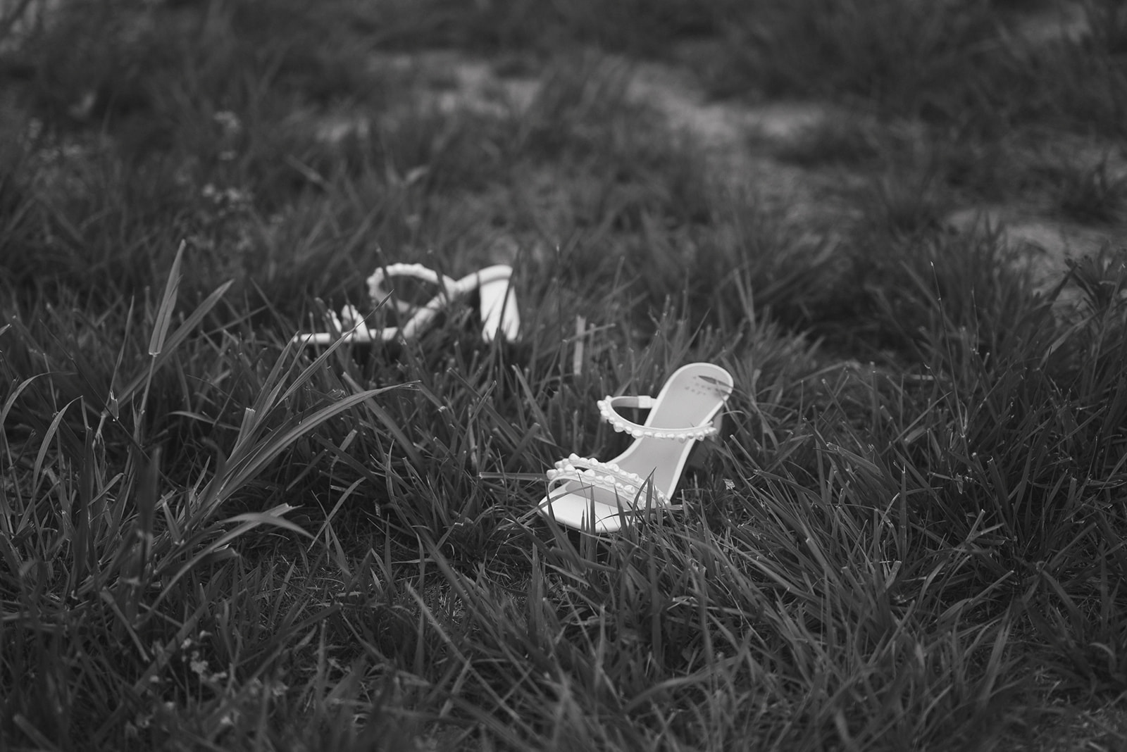 Black and white photo of a brides wedding heels in the grass