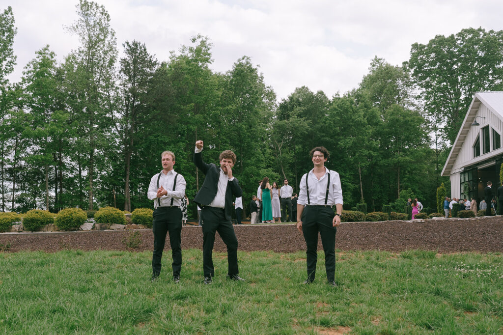 Groomsmen cheering on the bride and groom during their outdoor portraits