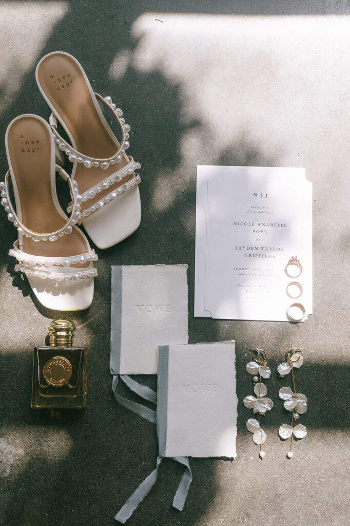 Wedding detail shot with invitations, shoes, perfume, and jewelry. 