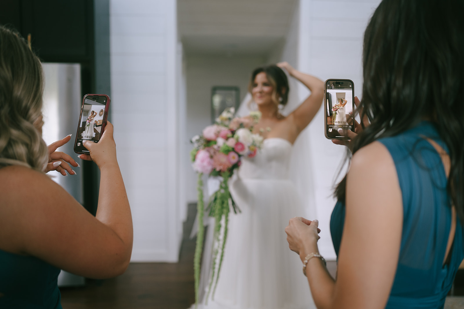 Bridesmaids taking photos of bride on their iPhones 