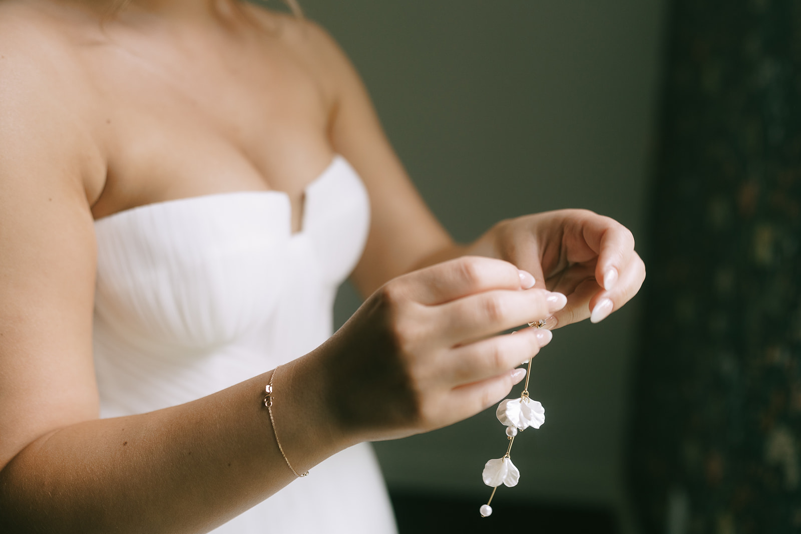 Bride holding her white floral earrings