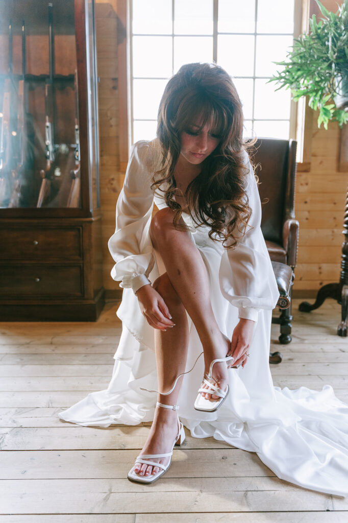 Bride putting her shoes on as she gets ready for her weddings day