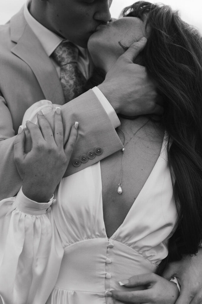 Black and white close up shot of a bride and groom kissing as the groom caresses the brides neck. - Planning The Perfect Wedding Photography Timeline