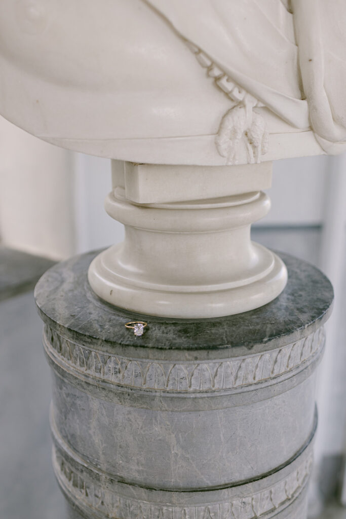 An engagement ring sitting on a statue in Lake Como