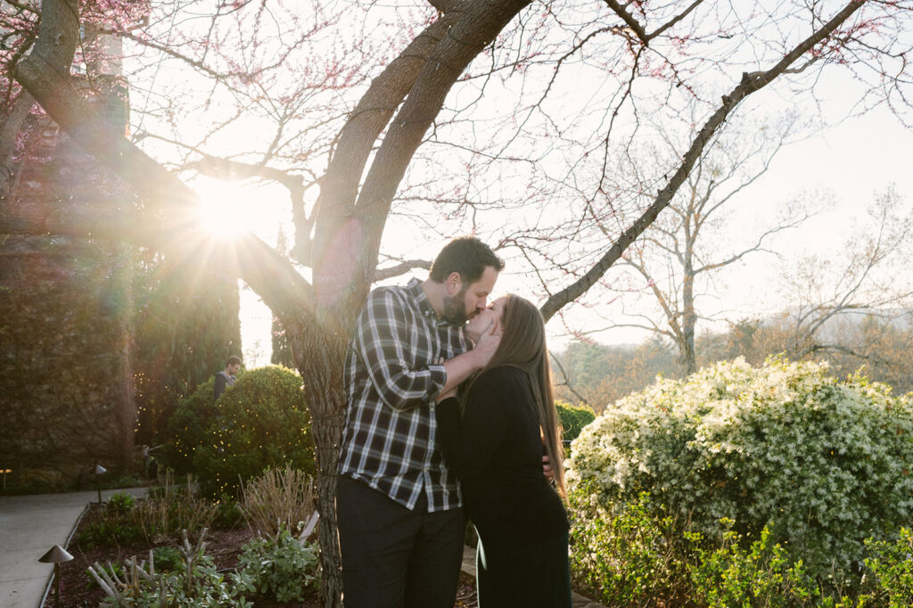 golden hour picture of the newly engaged couple kissing