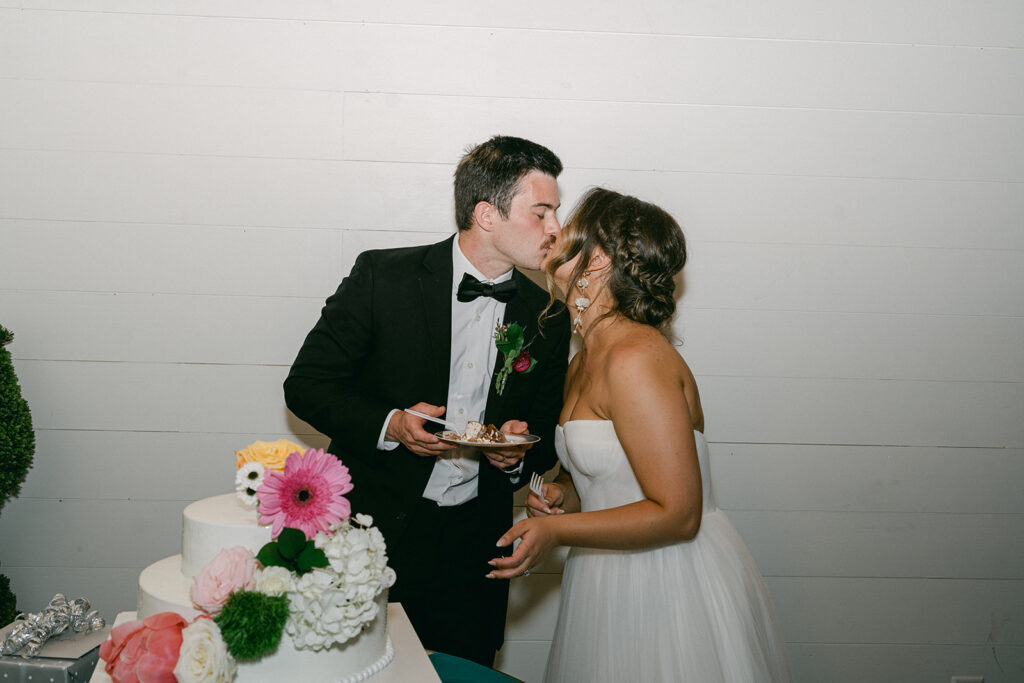 bride and groom kissing after cutting their wedding cake