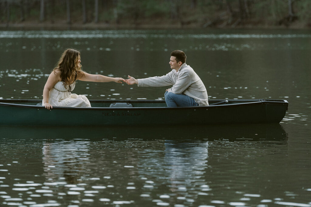 couple holding hands while canoeing