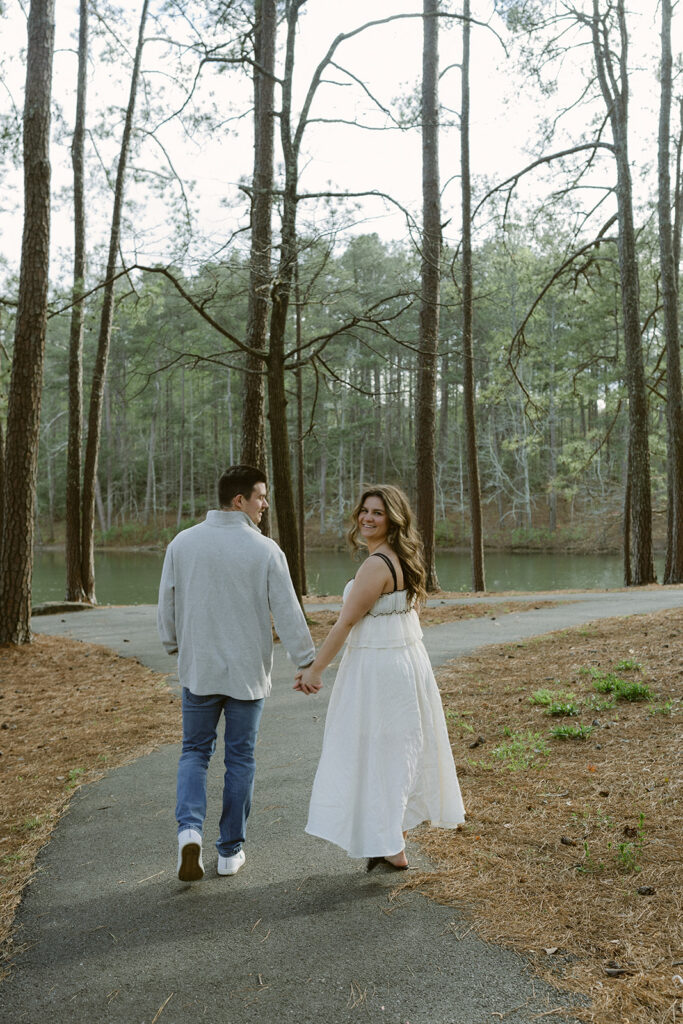 happy newly engaged couple holding hands walking around lake Allatoona 