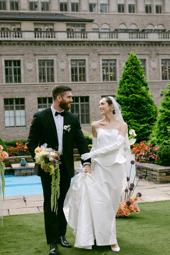 bride and groom holding hands walking around their wedding venue at 620 loft & garden