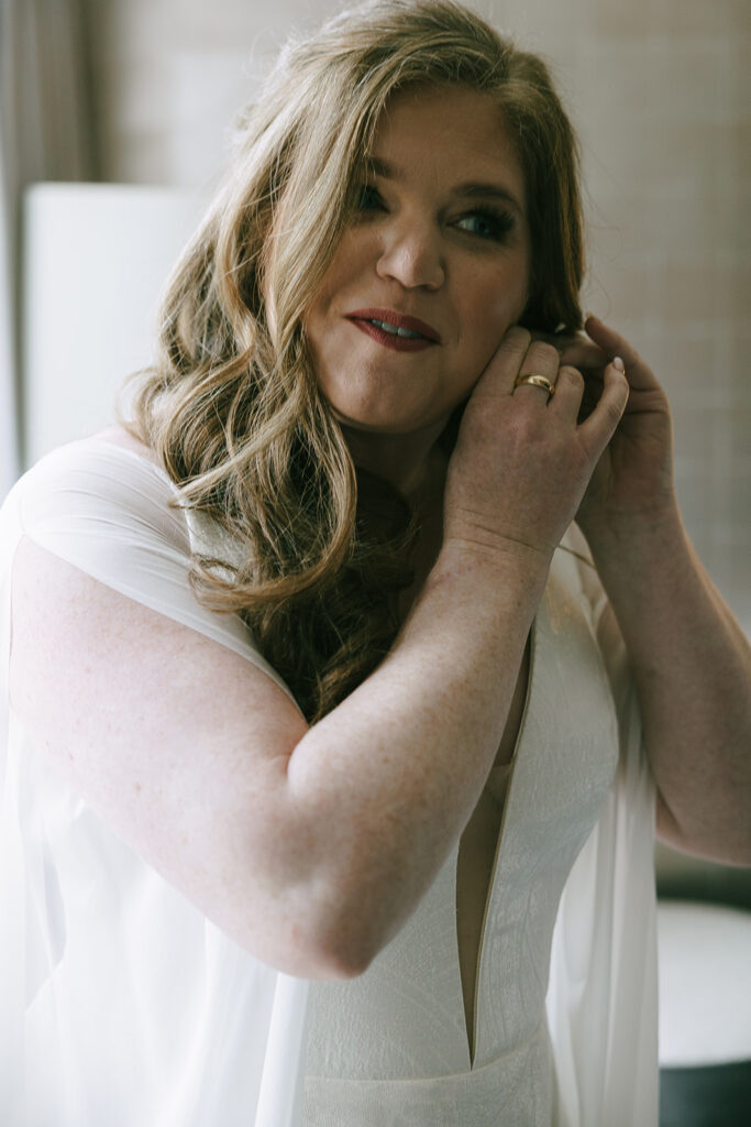 bride putting on her earrings for her intentional wedding day