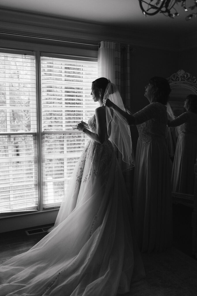 mother of the bride helping her with the wedding dress