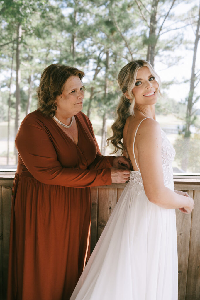 mother of the bride helping her with the wedding dress