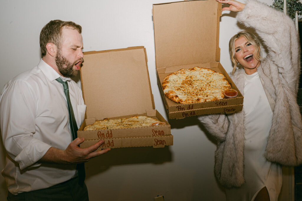 couple eating pizza at their lake house wedding reception party