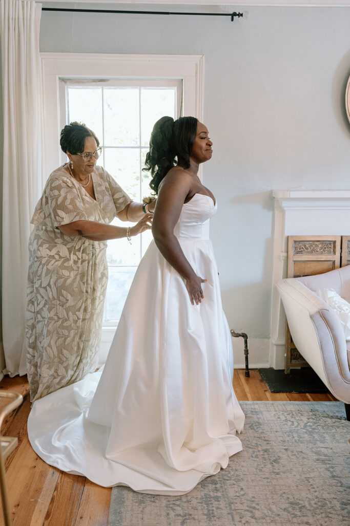 mother of the bride helping her with the wedding dress