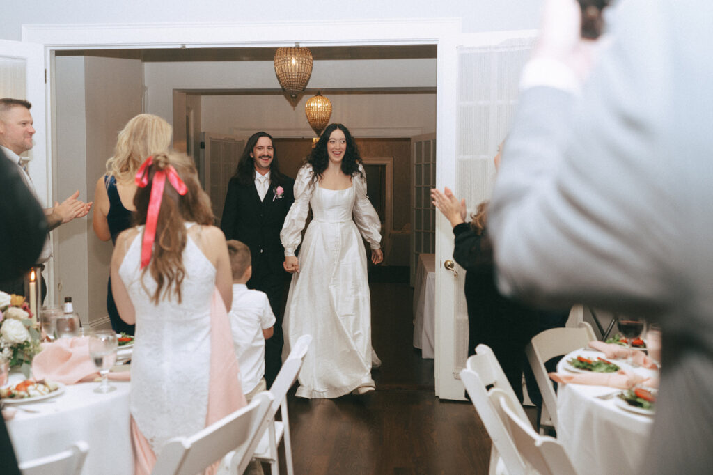 cute couple entering their coquette themed wedding reception